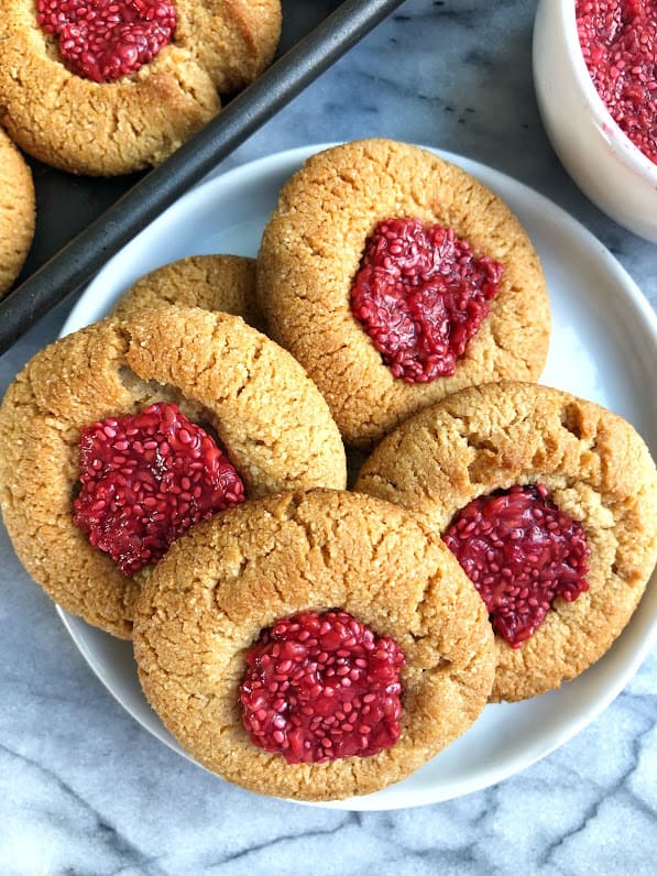 four paleo thumbprint cookies with chia jam on a plate 