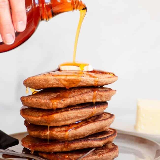 pouring syrup on stack of oatmeal blender pancakes