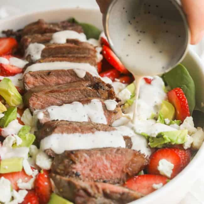 pouring dressing on strawberry steak salad