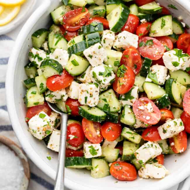 tomato cucumber salad in bowl with spoon