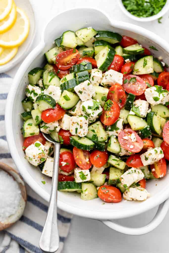 tomato cucumber salad in bowl with spoon