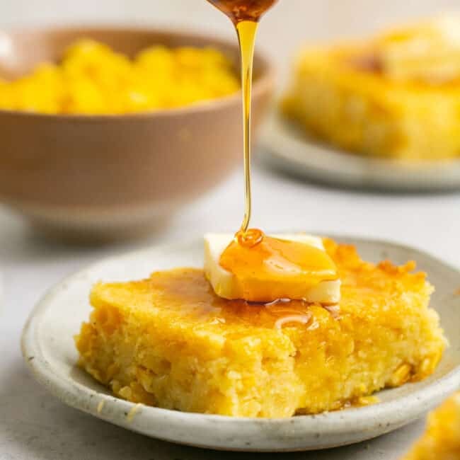 corn pudding on plate with butter and honey drizzle