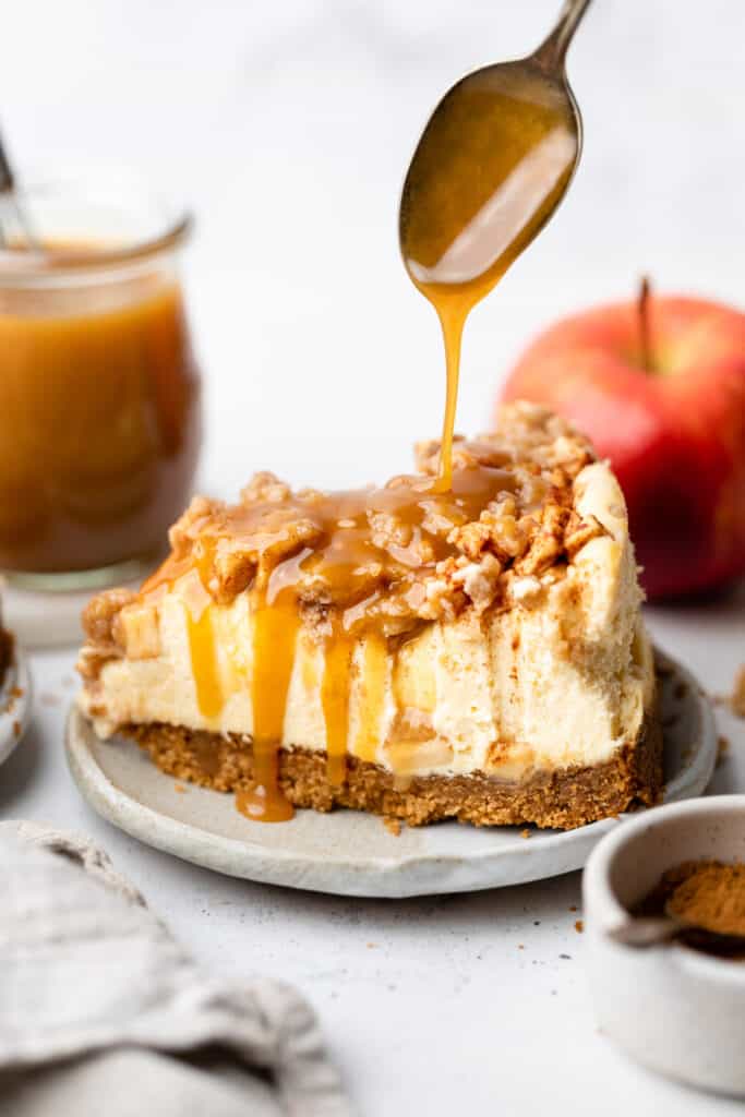 slice of apple cheesecake on plate with caramel drizzled on it