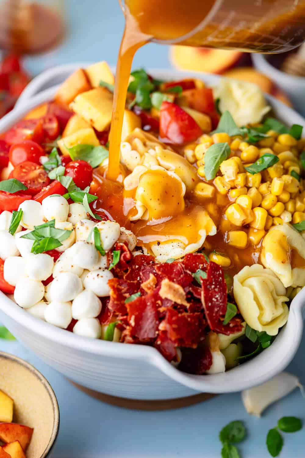 pouring dressing on tortellini pasta salad