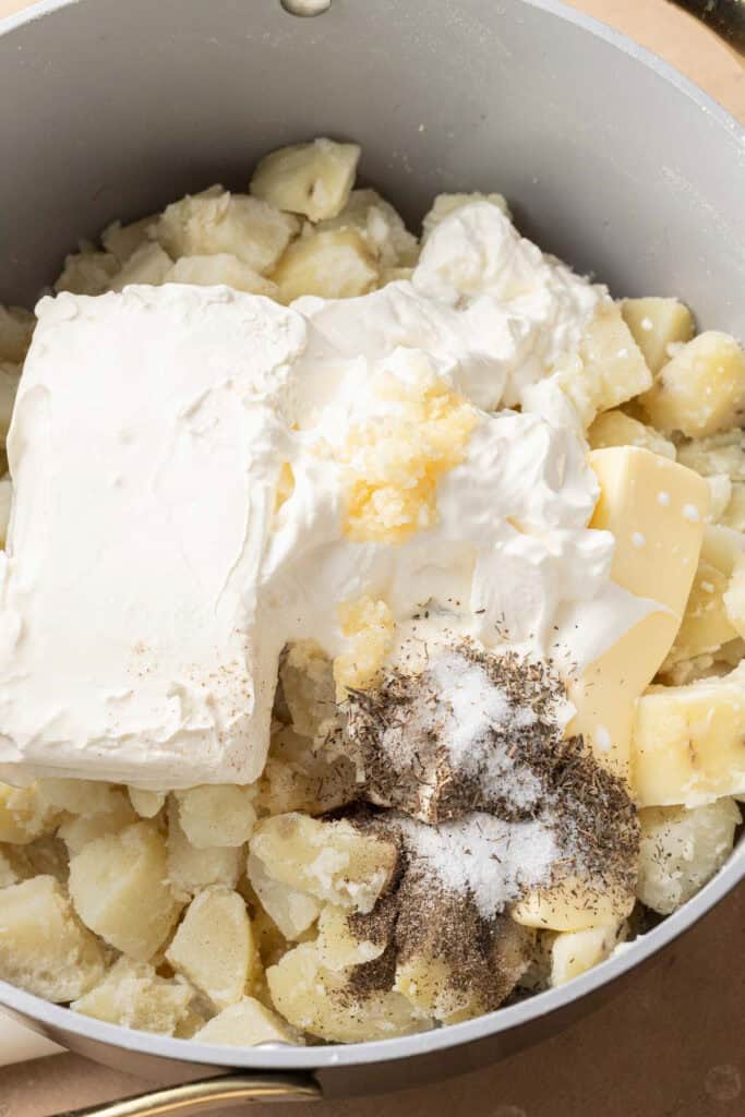 Large dutch oven with diced potato, cream cheese, butter, sour cream, milk, garlic, salt, pepper, and thyme