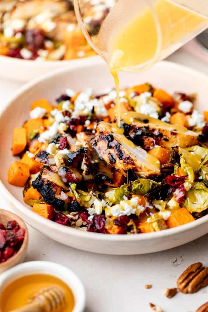 Pouring dressing on the Fall Harvest Chicken Bowl