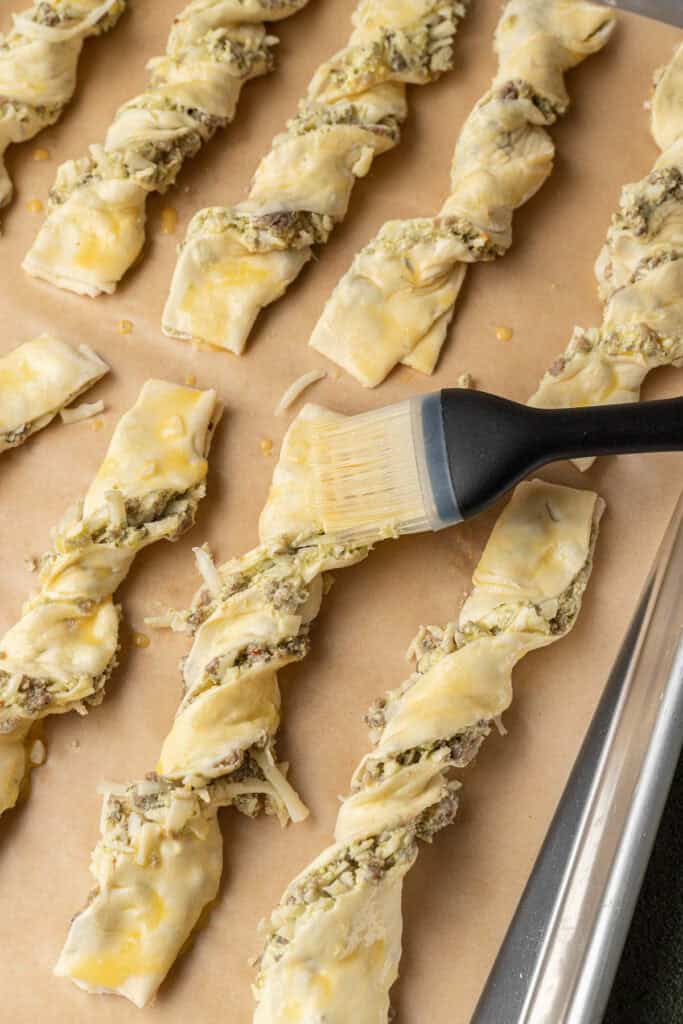 Brushing each pastry with egg wash