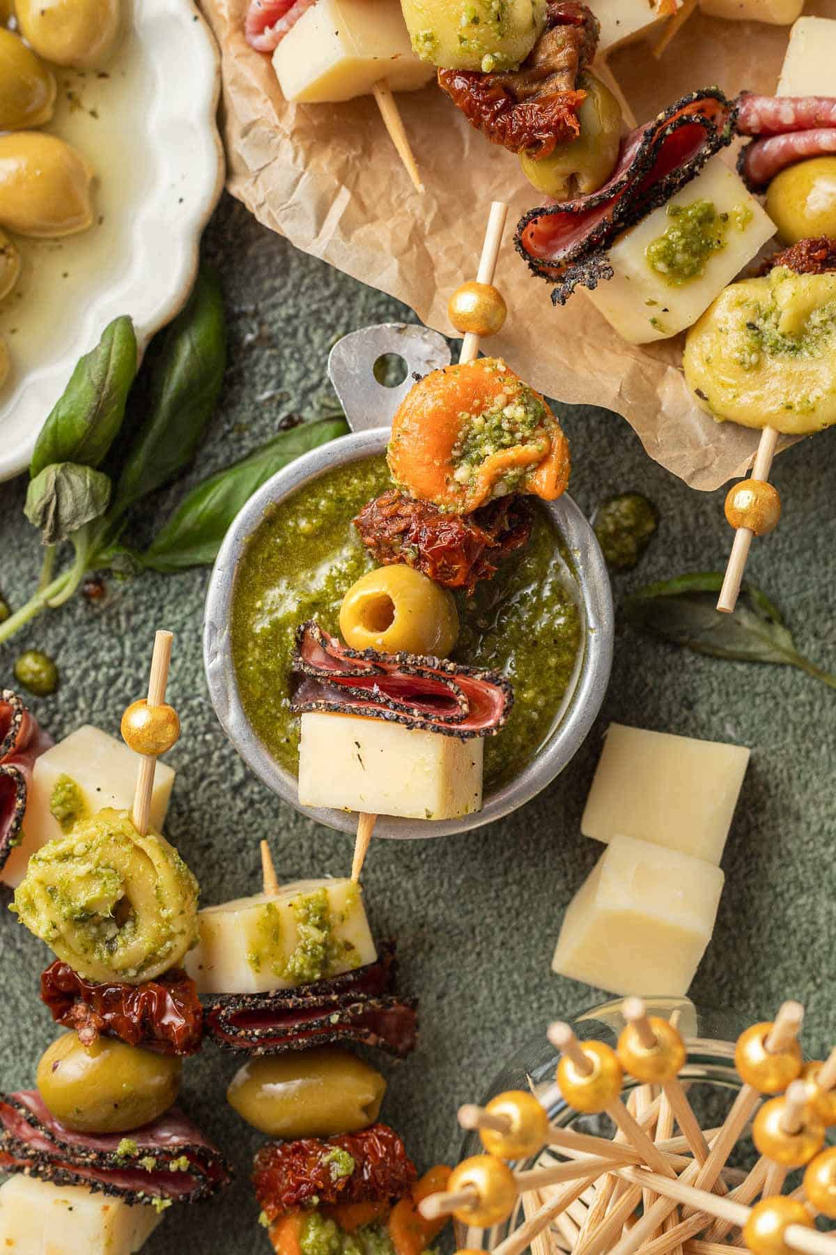 Pesto Tortellini Bites cheese, salami, olive sundried tomato and tortellini on a toothpick.
