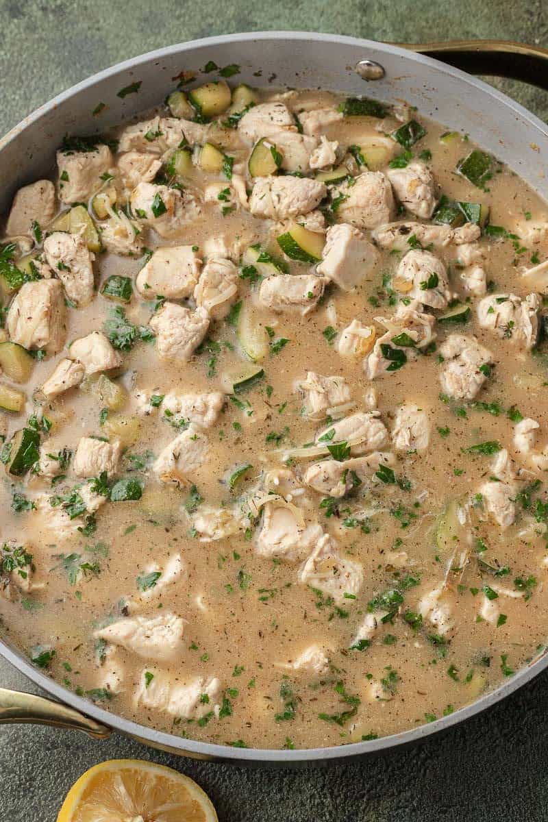 Adding in parsley, thyme, salt, and pepper, rice, chicken stock, lemon juice, and parmesan cheese