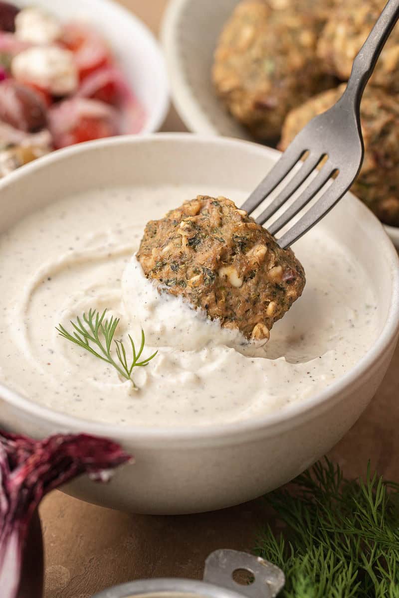 dunking lemon dill meatballs in garlic sauce