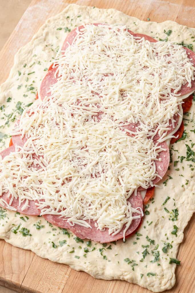 pepperoni, provolone and salami on top of the pizza dough