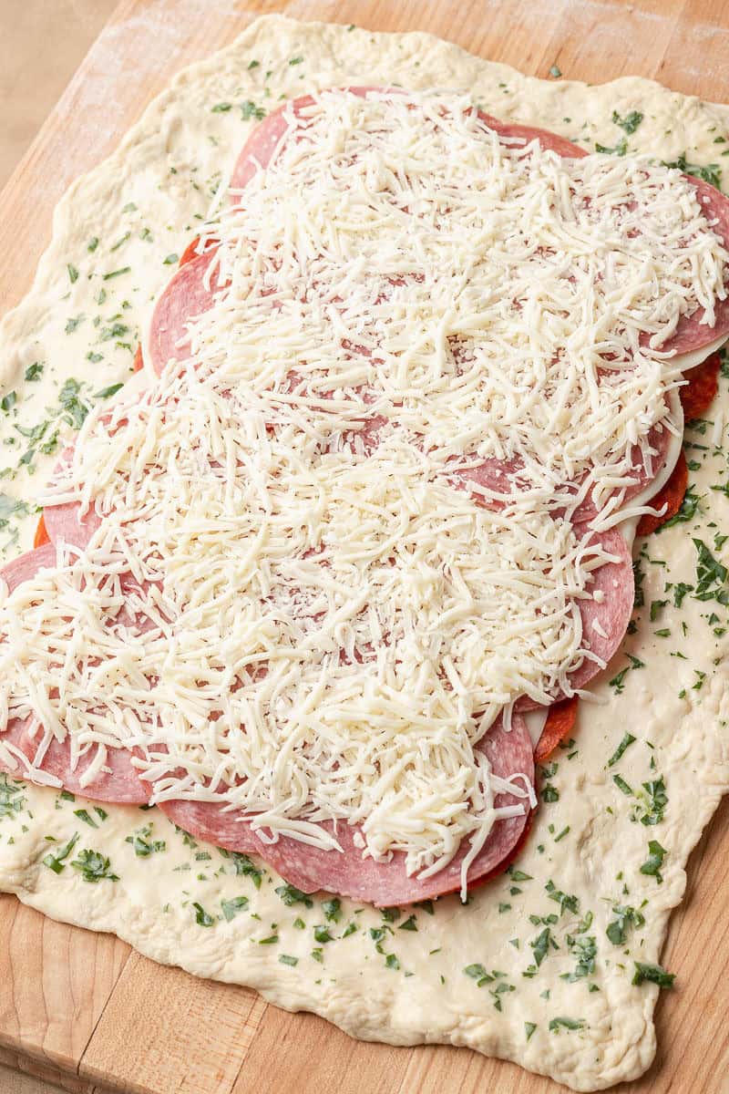 pepperoni, provolone and salami on top of the pizza dough