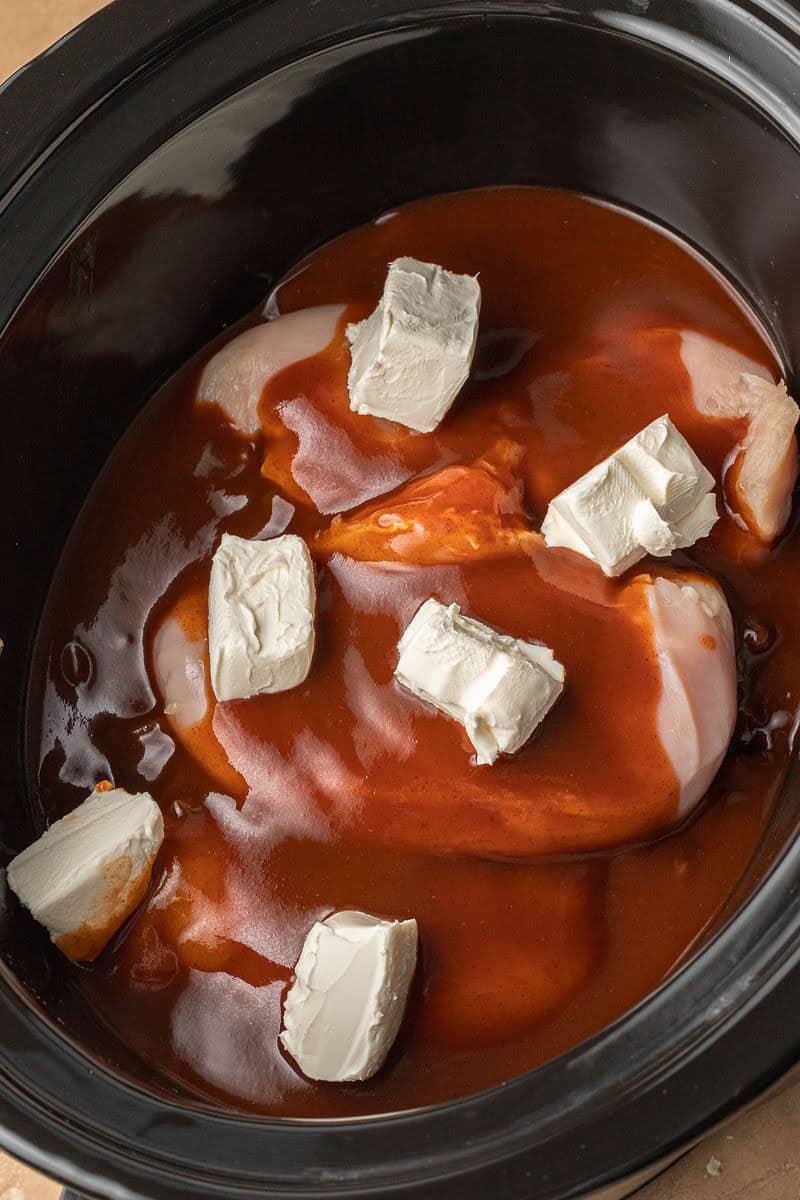 Chicken breasts and enchilada sauce added to slow cooker