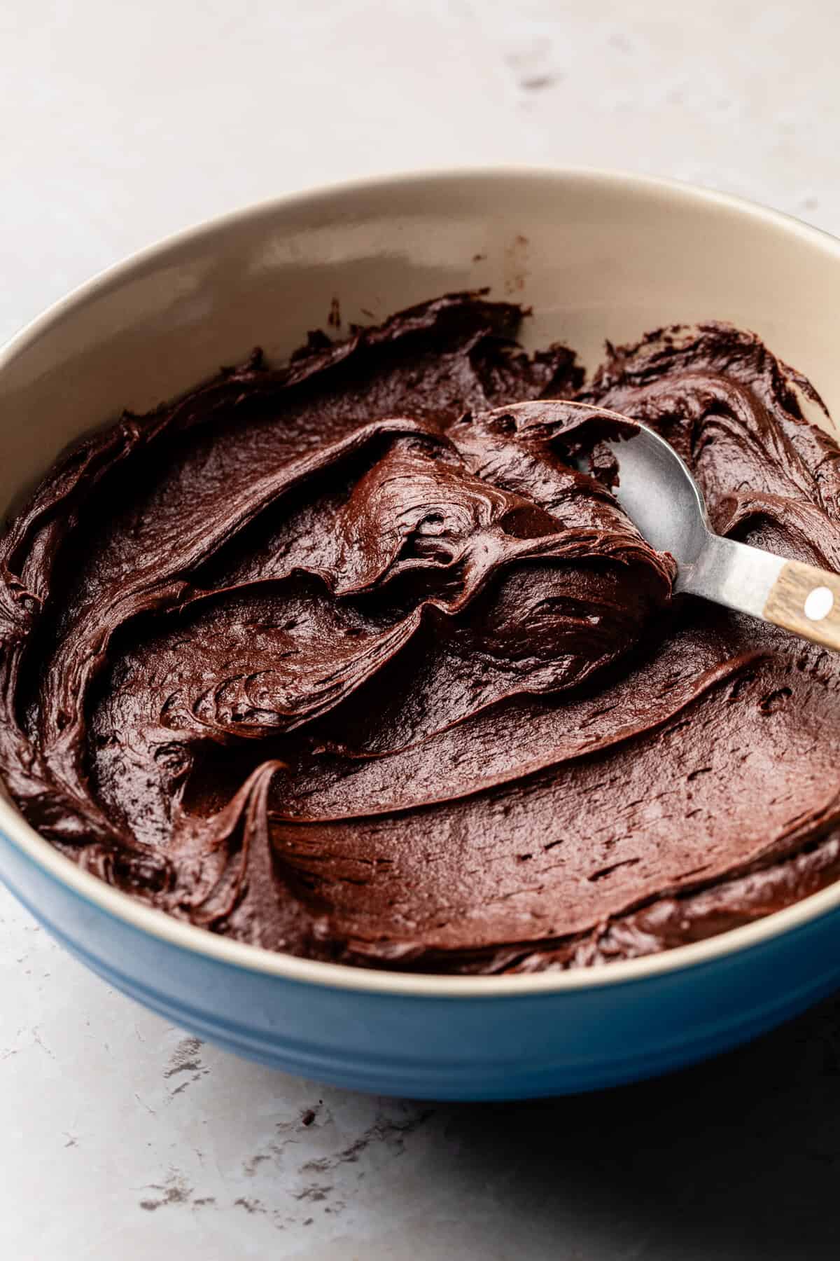 Chocolate frosting in bowl with spoon