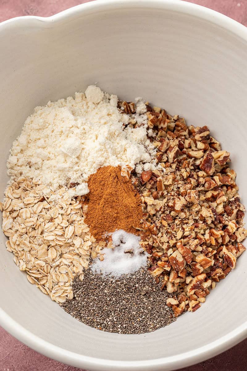Oats, pecans, protein powder, chia seeds, cinnamon, and salt in bowl
