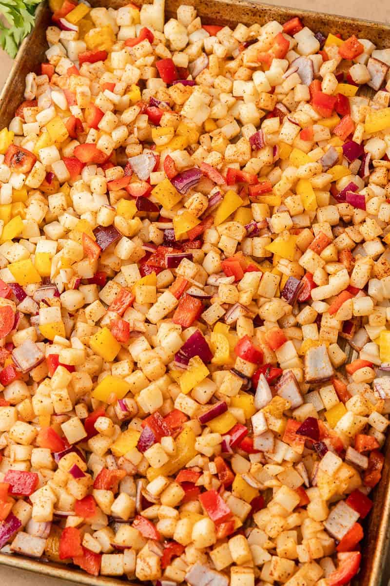 Large sheet pan with diced onion, peppers, and potatoes