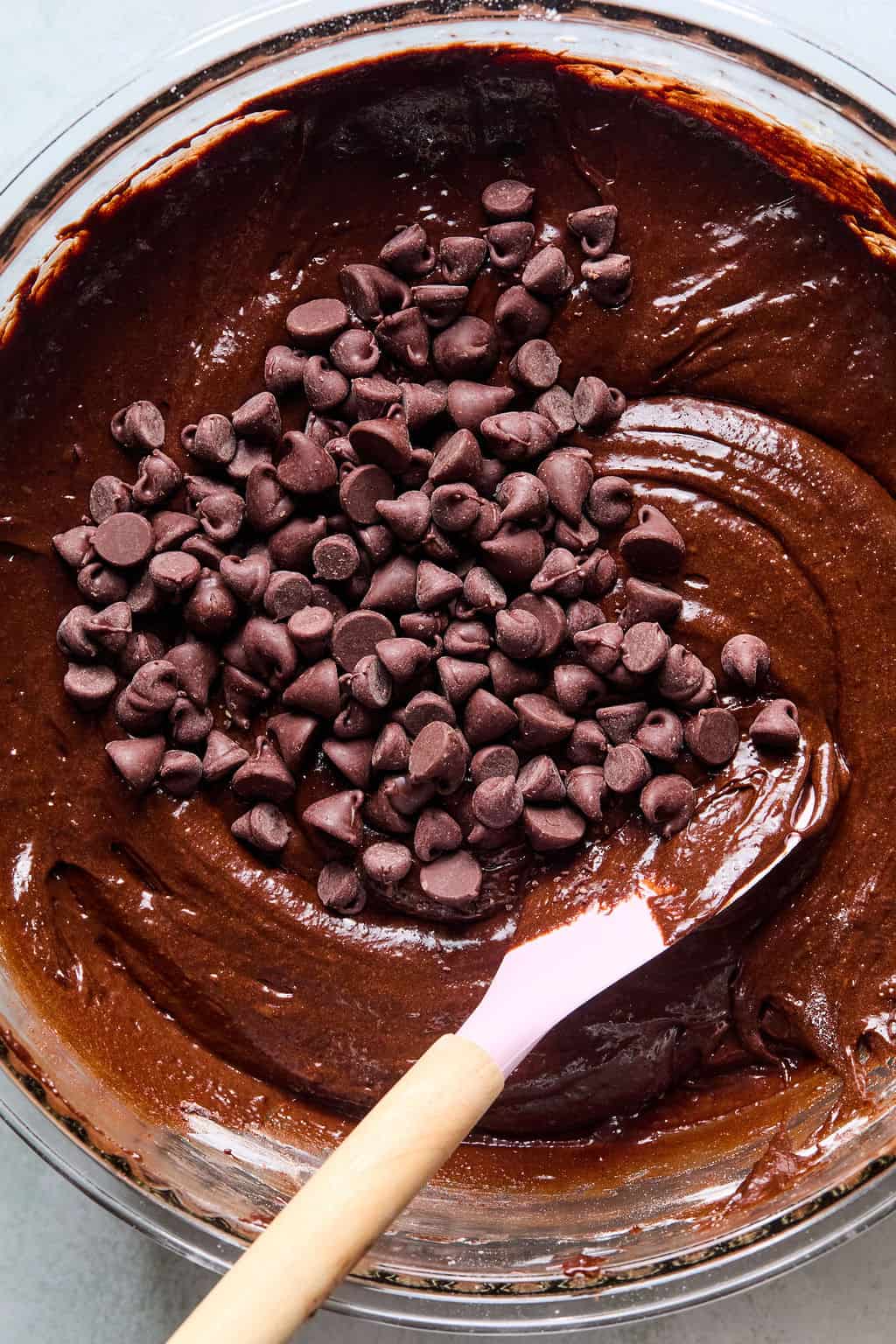 Adding in chocolate chips to brownie batter in bowl.