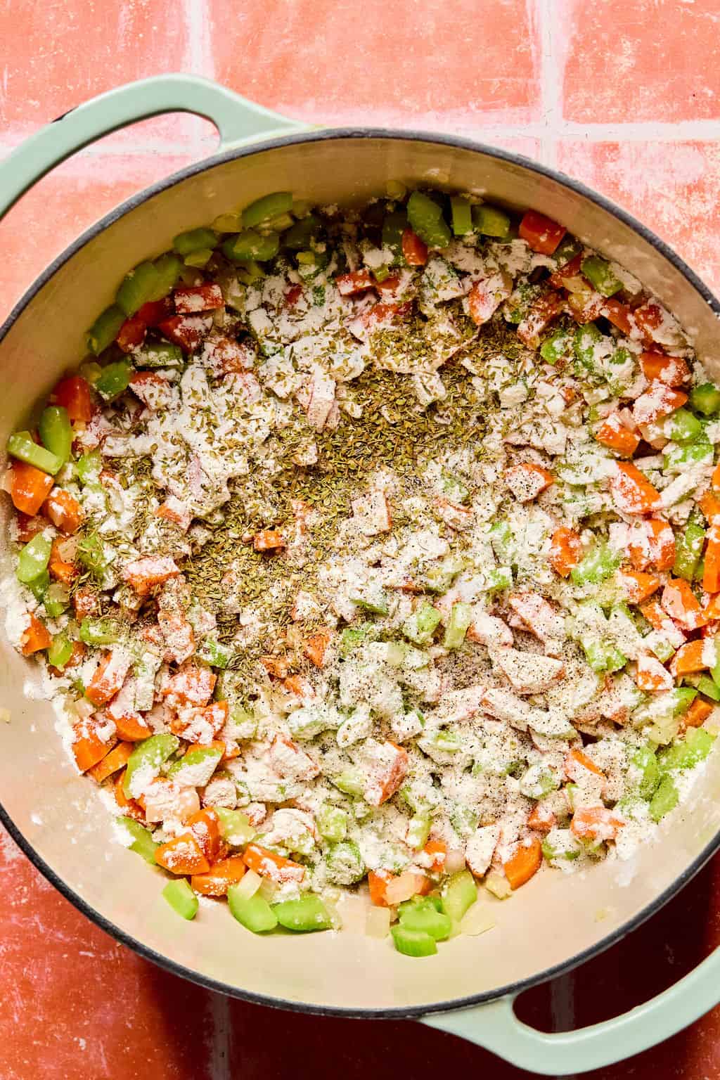 Large Dutch oven with flour, thyme, oregano, salt, and pepper added.
