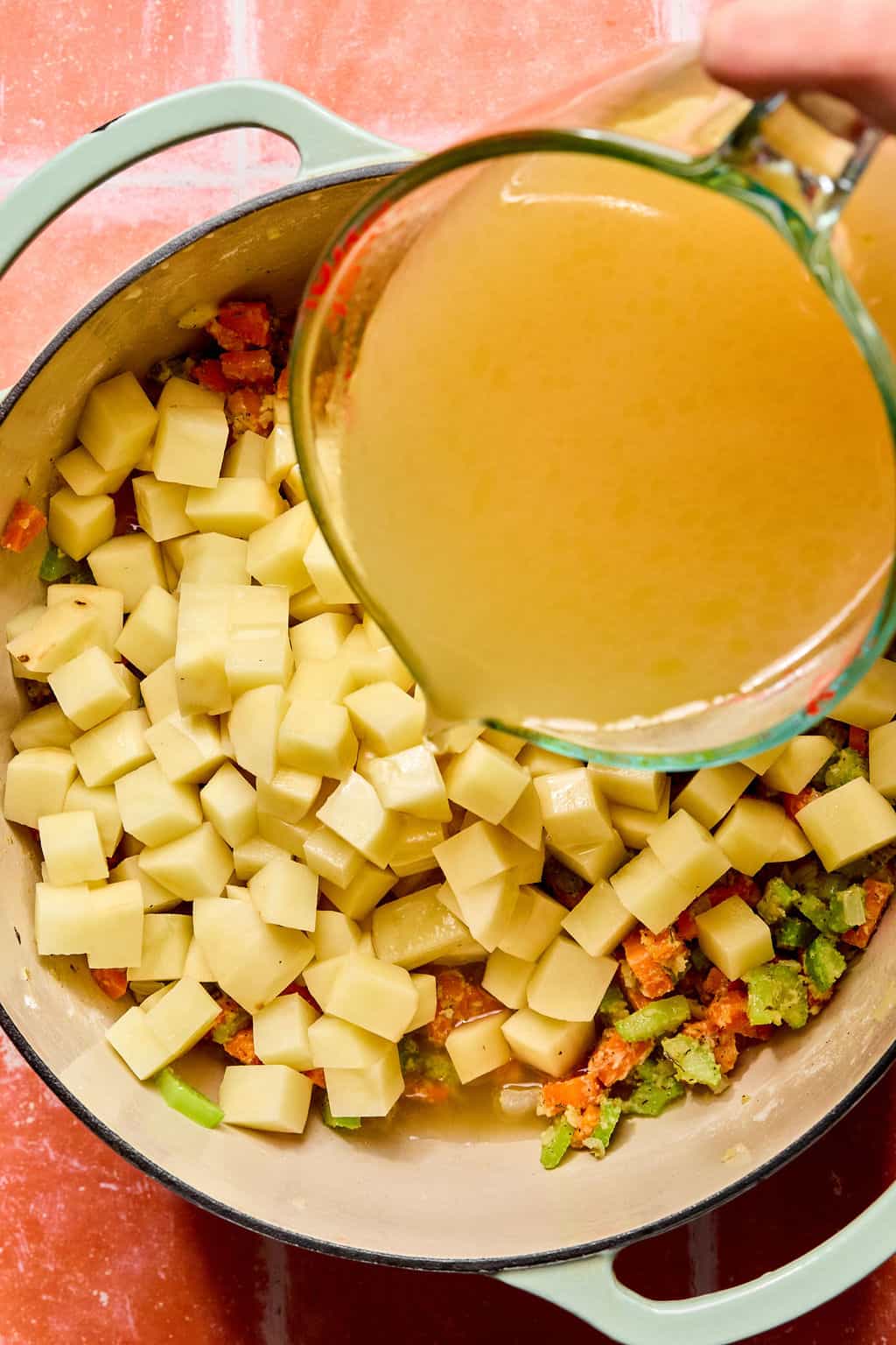 Pouring chicken broth into large Dutch oven.