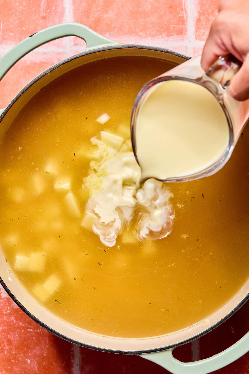 Pouring whole milk into large Dutch oven.
