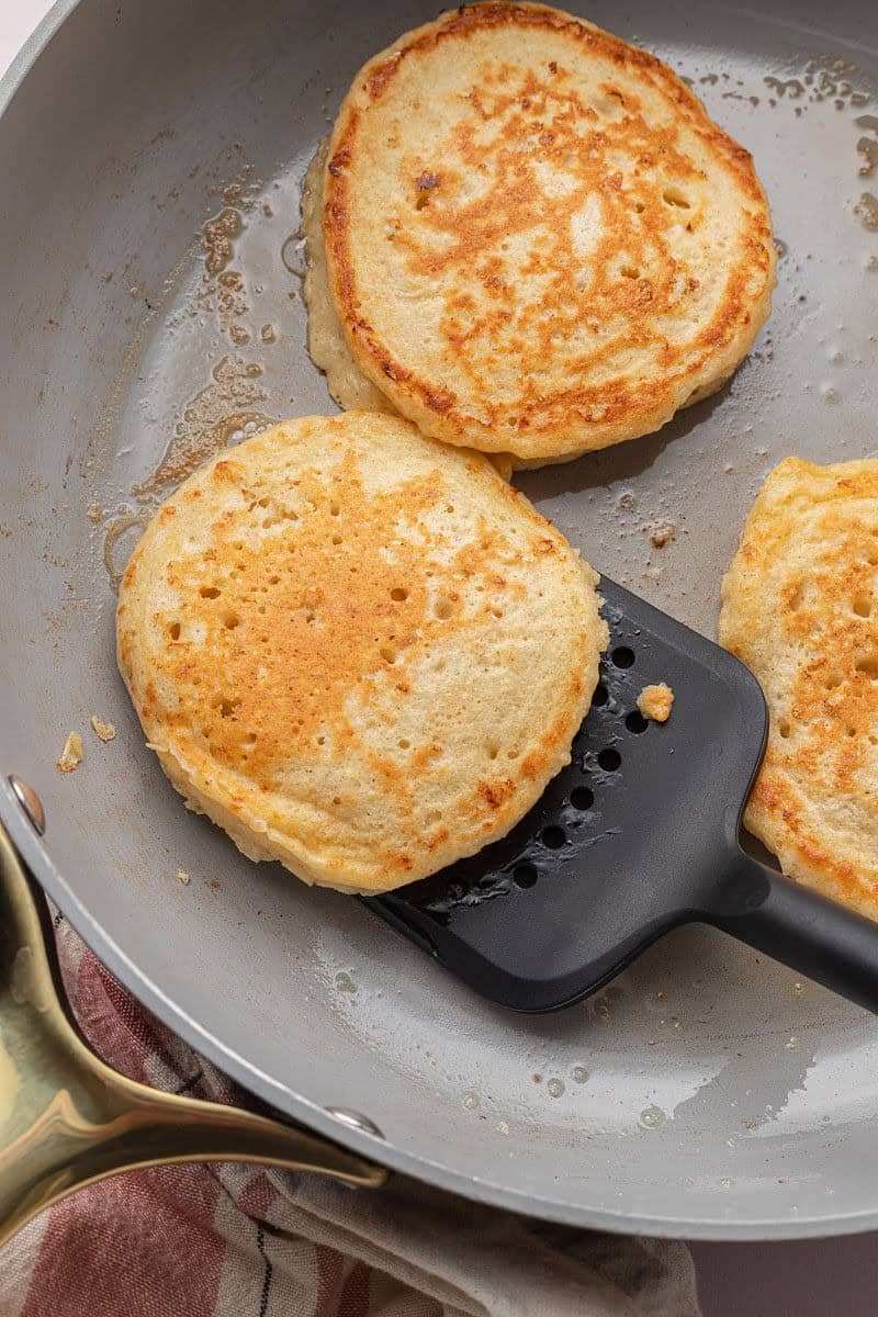 High Protein Pancakes in large skillet with black spatula.