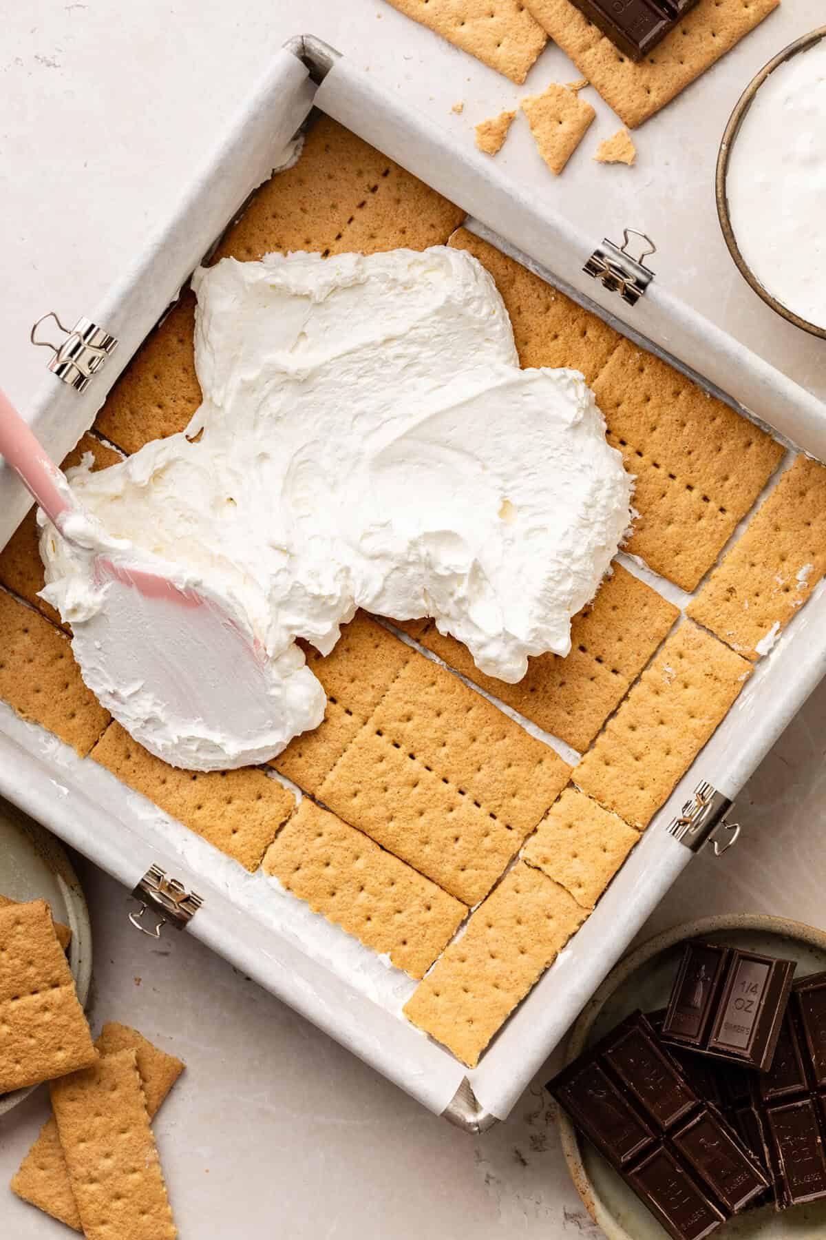 Spreading cool whip and marshmallow topping on top of graham crackers.