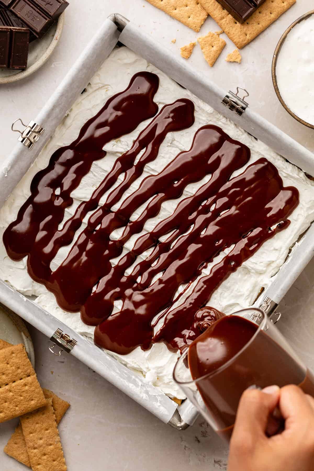 Pouring chocolate on top of pan mixture.