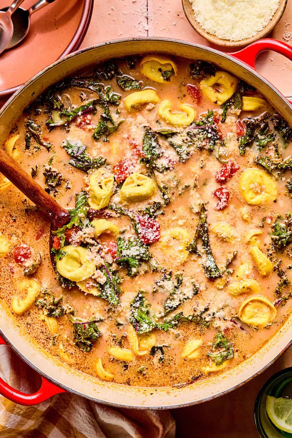 Spicy Sausage Tortellini Soup in large Dutch oven with wooden spoon.