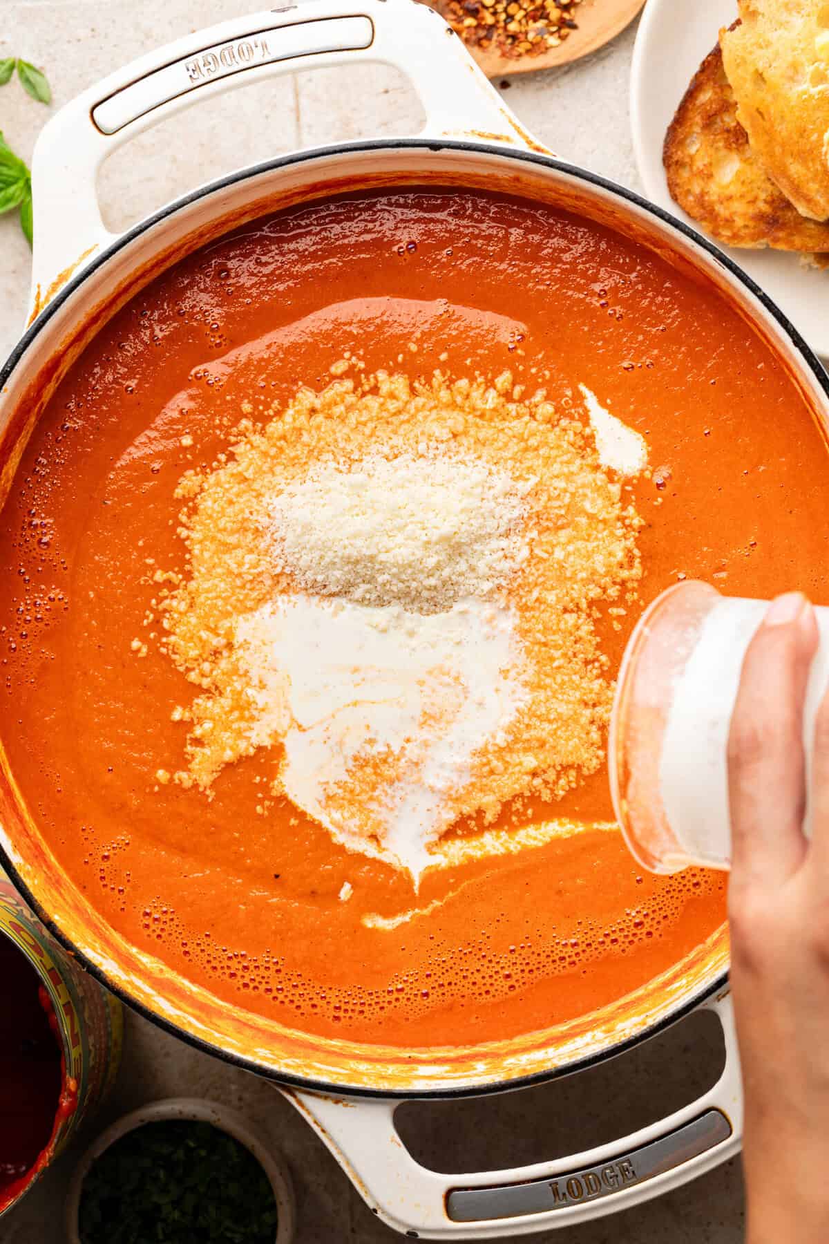 Adding heavy cream and parmesan cheese into sauce pan.