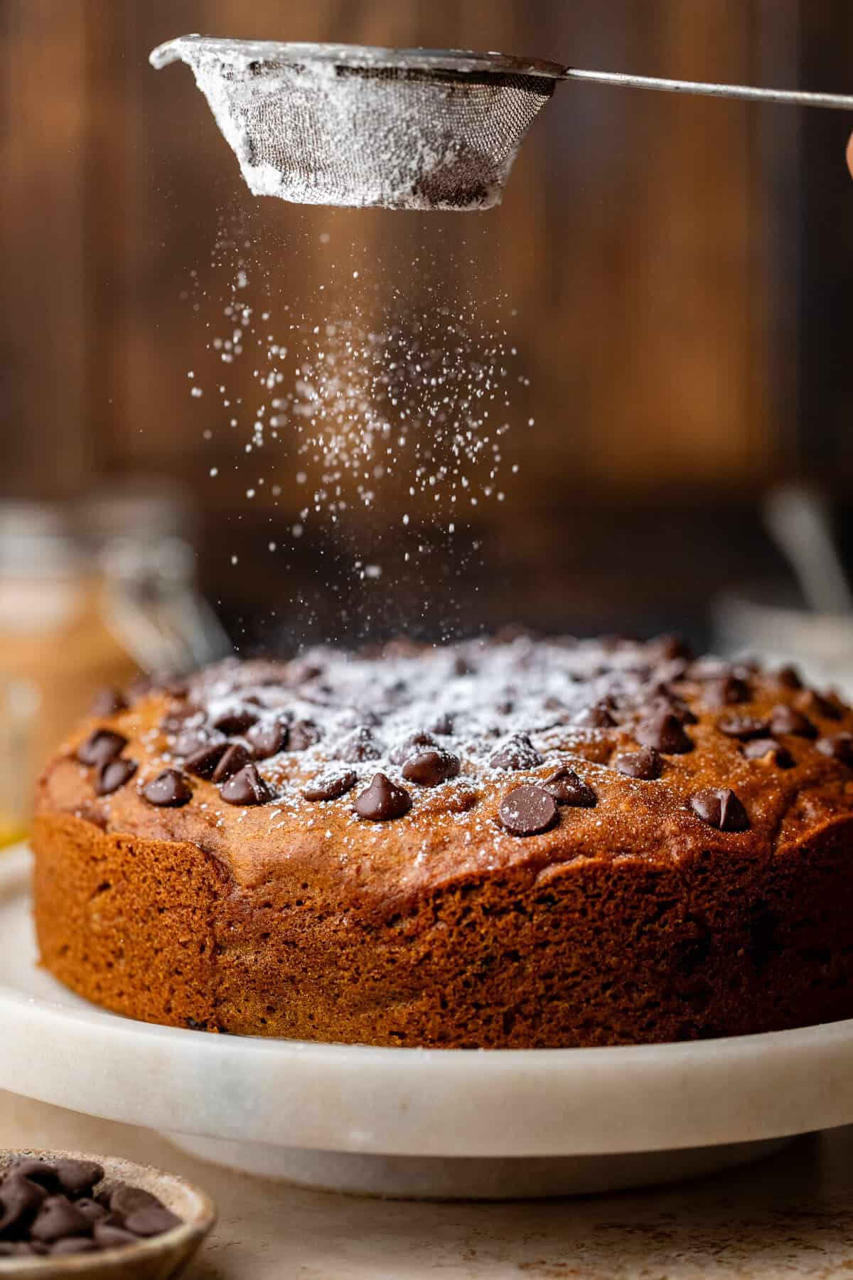 dusting powder sugar on pumpkin olive oil cake