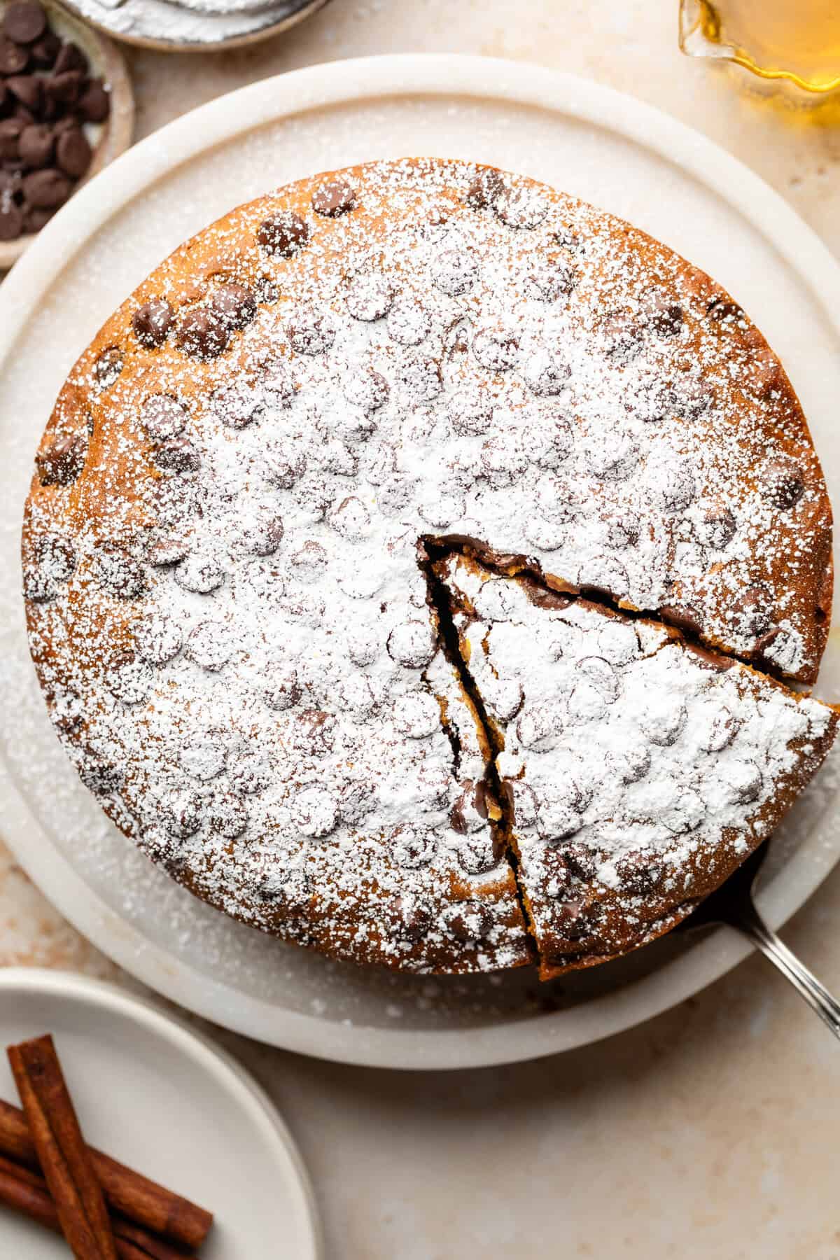 overhead shot of pumpkin olive oil cake with slice starting to be lifted away from cake