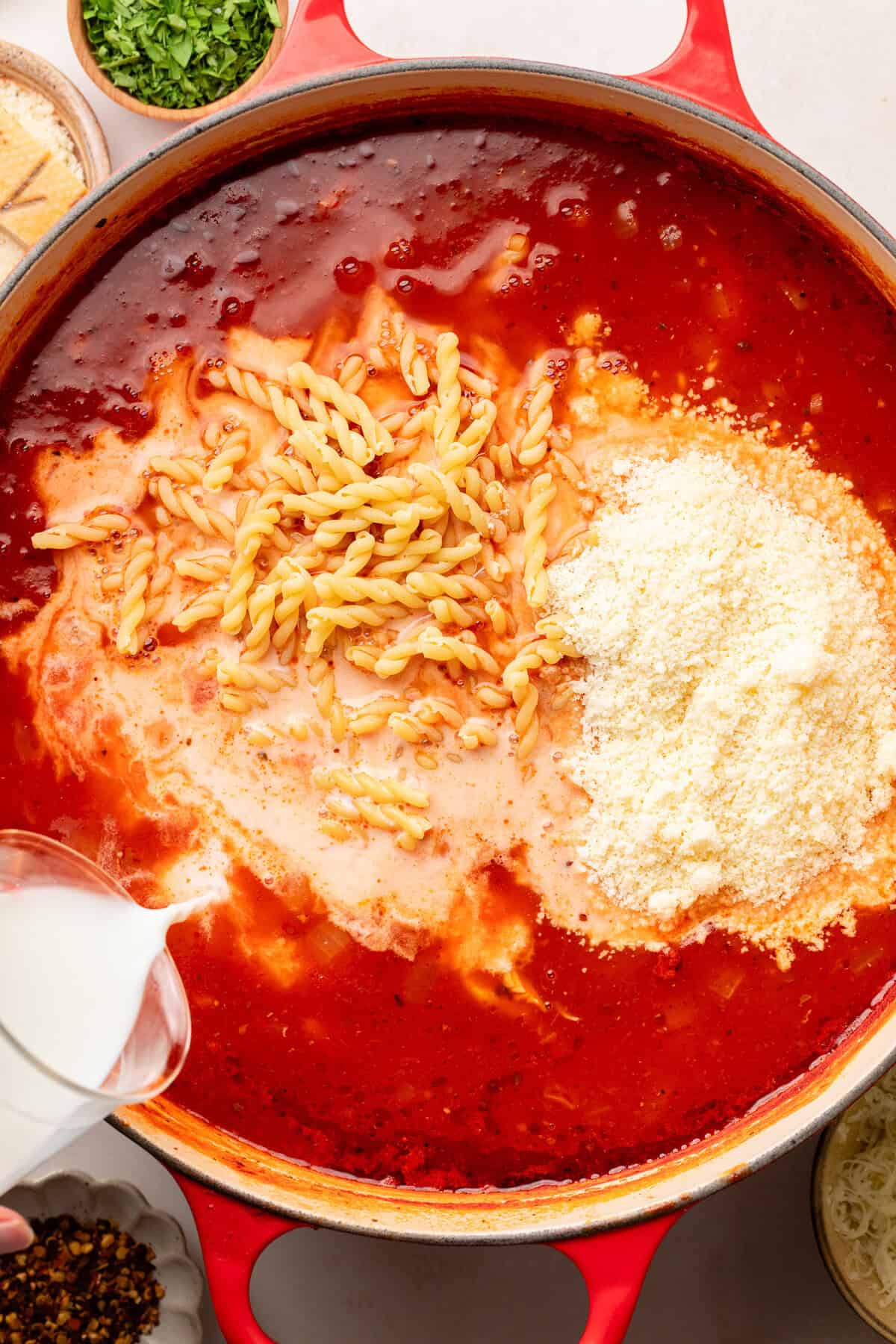 pouring milk into sauce pot with noodles and cheese