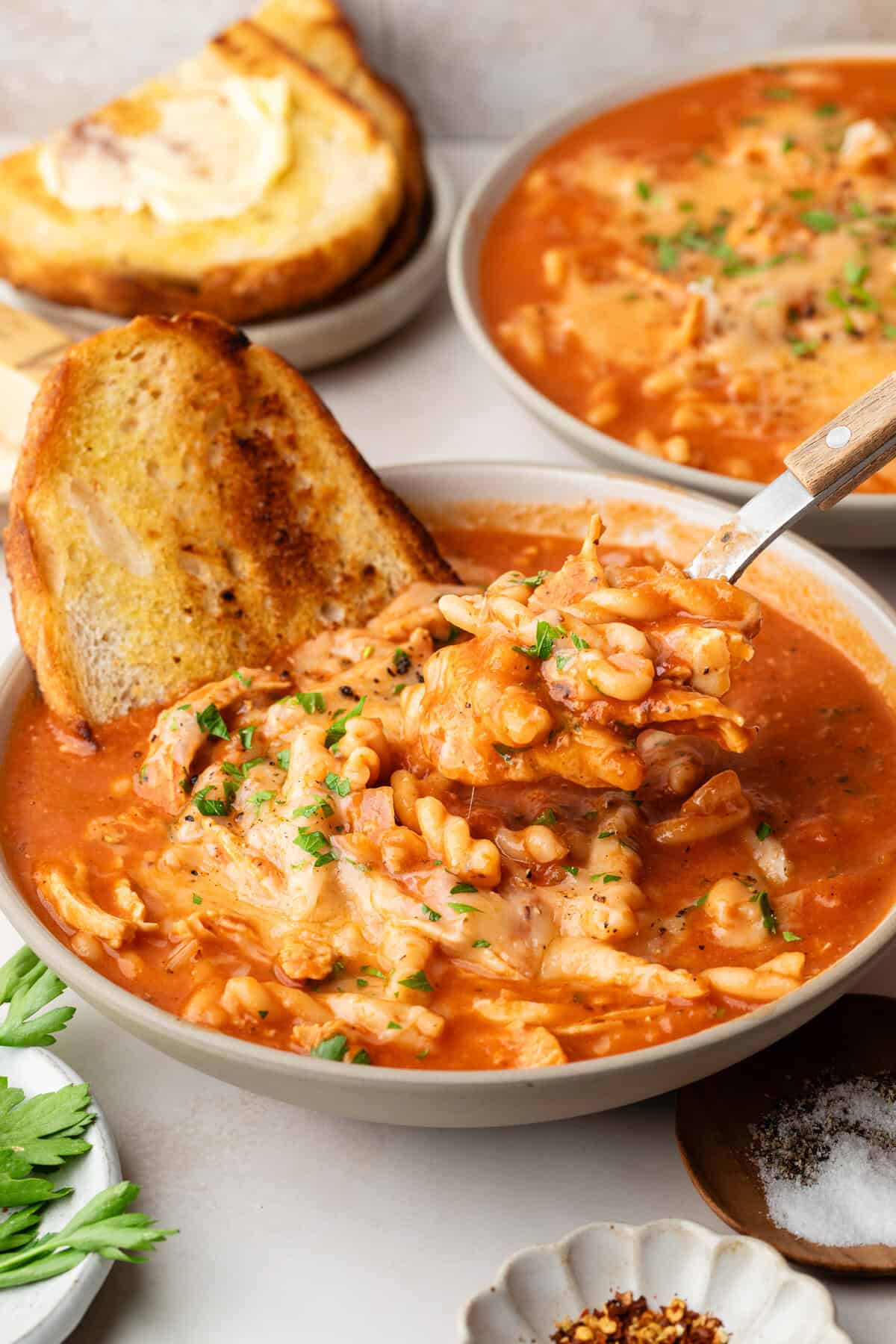 chicken parmesan soup in bowl with spoon and toast