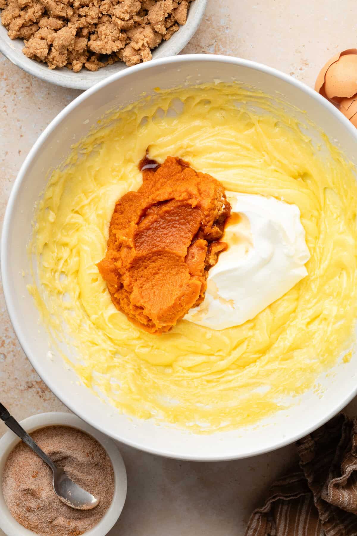 pumpkin and sour cream in a bowl on top of creamed butter and sugar